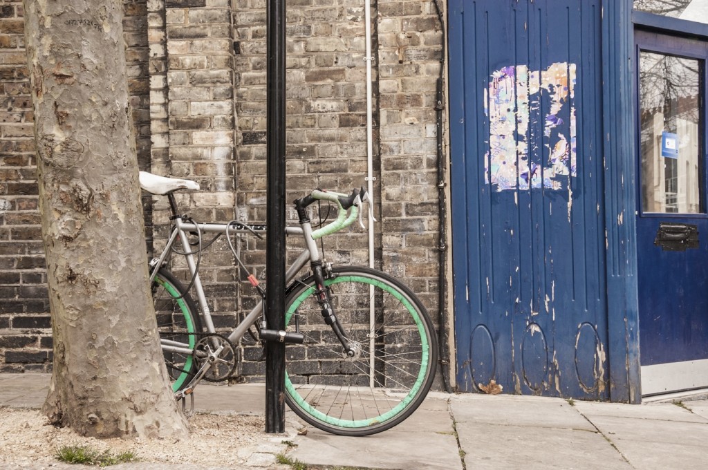 Cool single gear road bycicle locked to a street lamp in front o