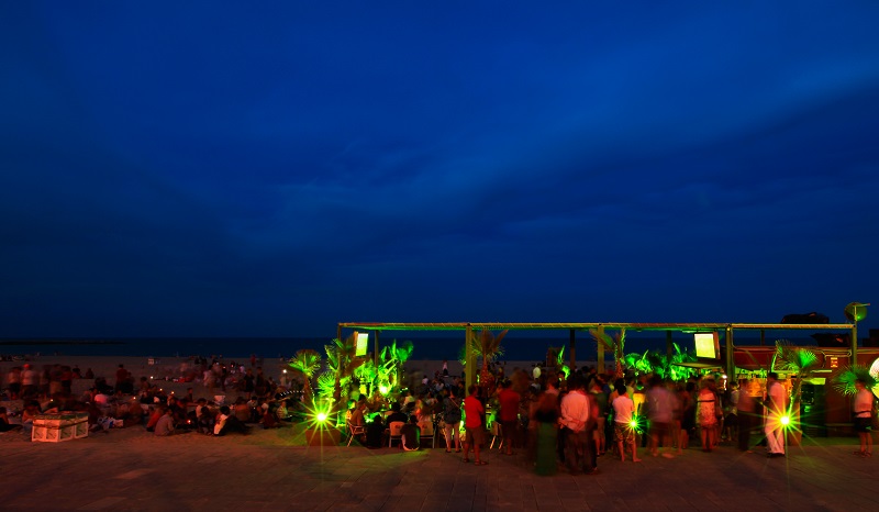 Beach at Barcelona in twilight, people are motion blurred.