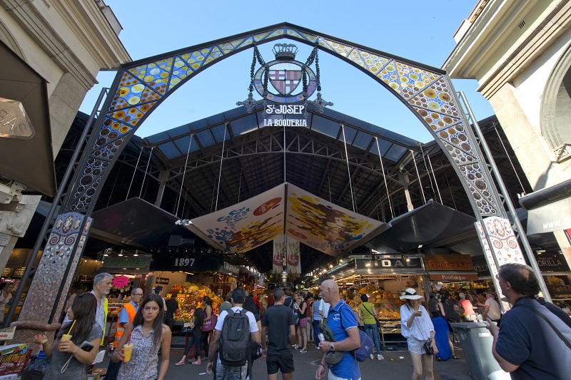 Barcelona, Spain - June 26, 2015: Tourists in famous La Boqueria market on June 26, 2015 in Barcelona. One of the oldest markets in Europe that still exist.