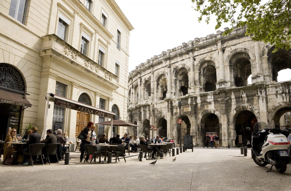 Nimes, France -- April 11, 2014: Cafe "Arena Cafe" near the Roman Arena, people are dining at the tables outdoors on a beautiful April day